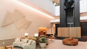 A modern lobby with a seating area, a reception desk, and a large abstract wall art piece.