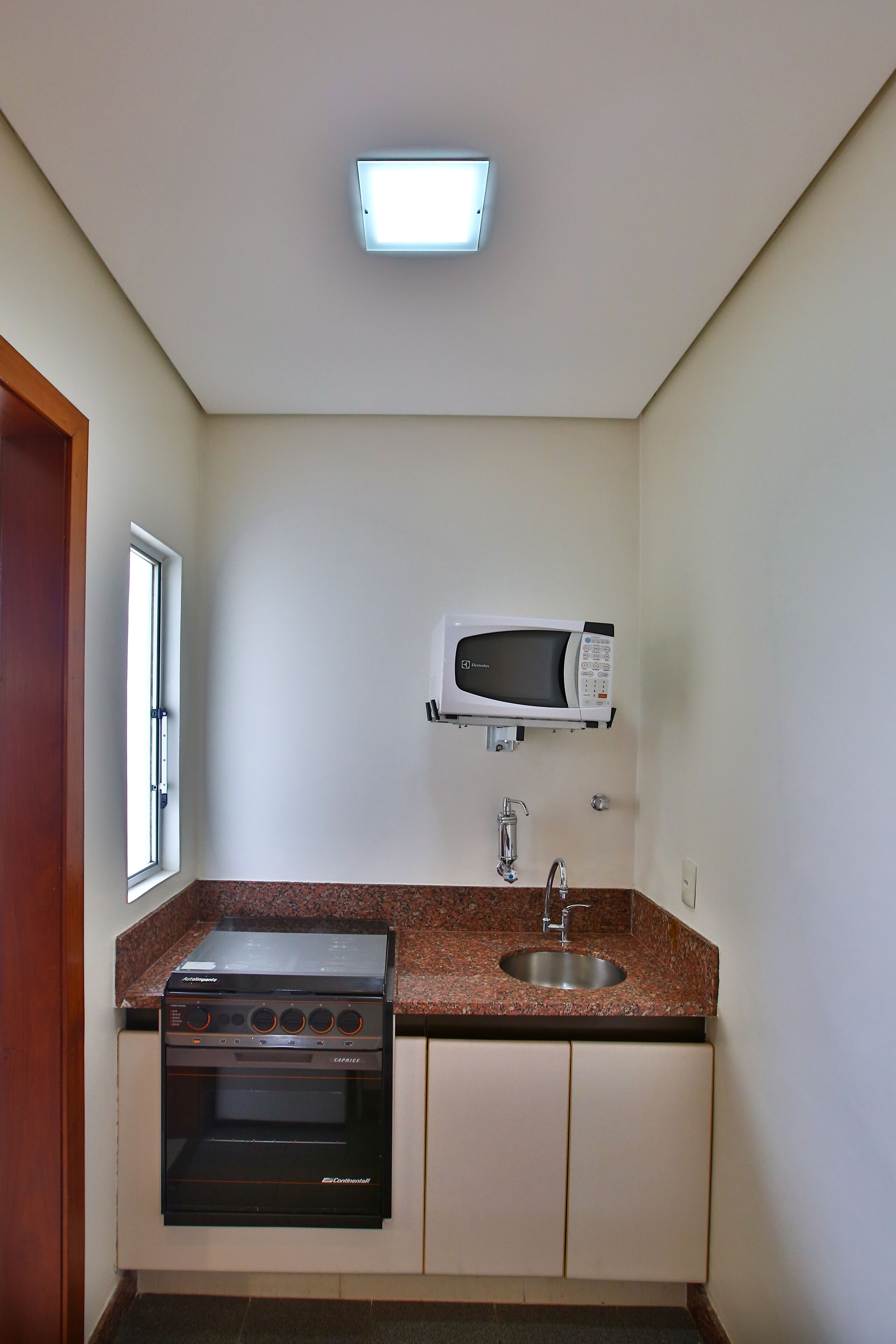 A compact kitchen with a built-in oven, microwave, and sink.