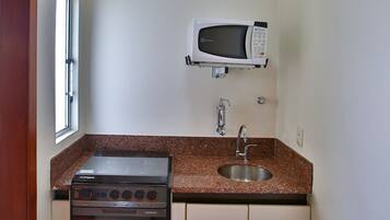A compact kitchen with a built-in oven, microwave, and sink.