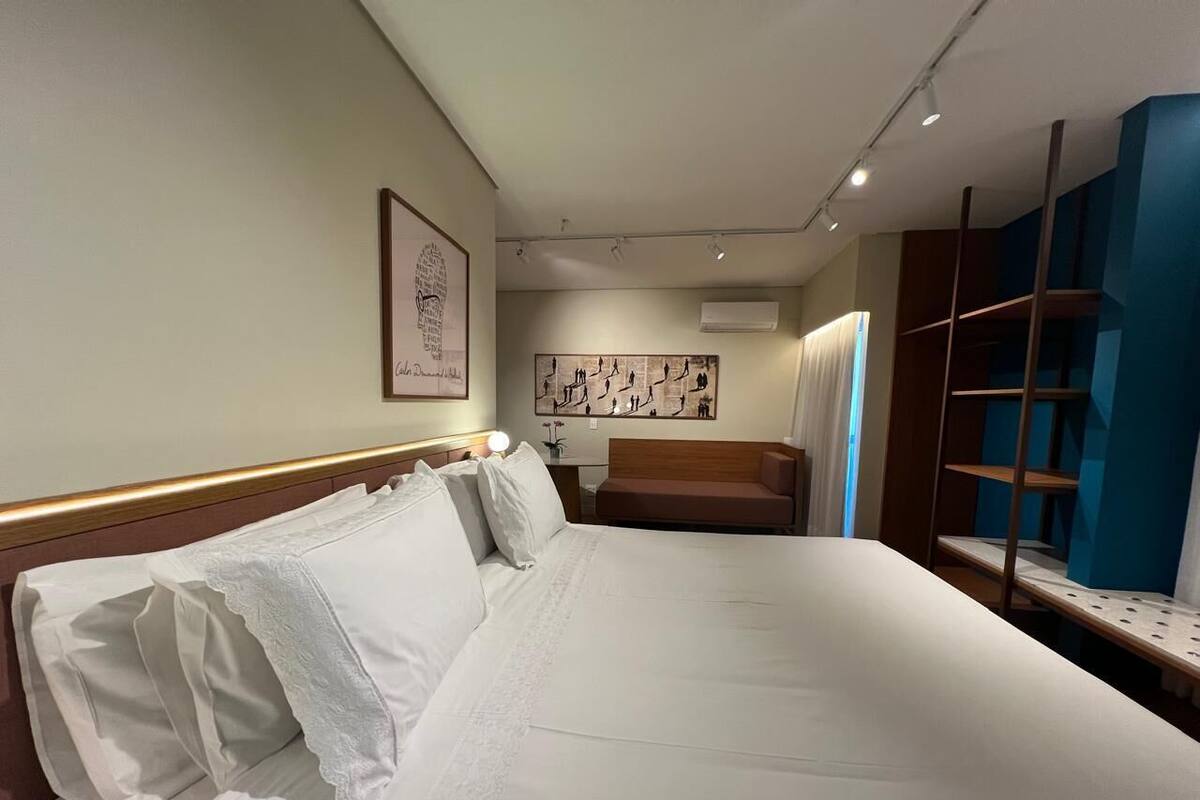 Una habitación de hotel con una cama grande, una mesita de noche, una silla y un armario.