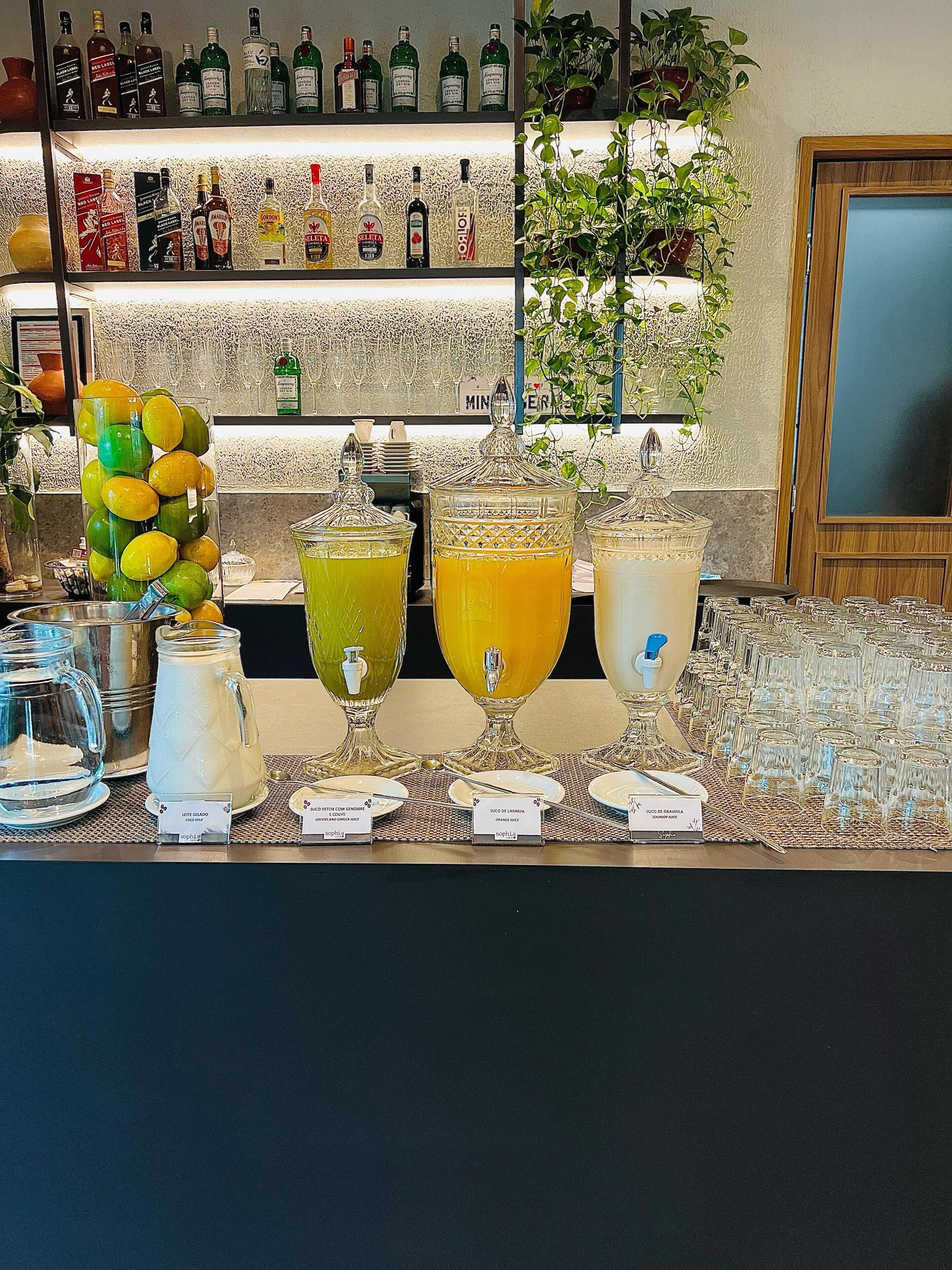 A bar area with various liquor bottles, a fruit display, and a selection of drinks in large glasses.