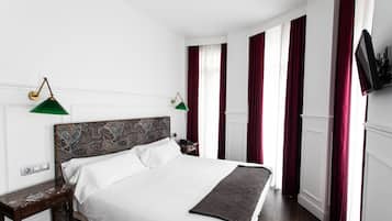 A neatly made bed with a patterned headboard, a bedside table, and a green lamp.
