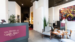 Zona de recepción con diseño moderno, que incluye un mostrador de recepción, asientos y una escalera que sube a un nivel superior.