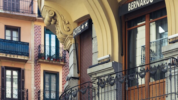 Fachada de hotel con un cartel que dice "BERNARDO HOTEL", destacando barandillas de hierro ornamentadas y una fachada de ladrillo.