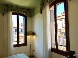 A room with two windows, a bed, and a floor lamp.