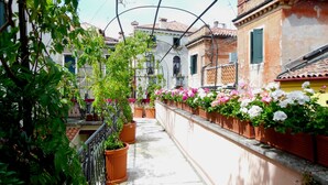 A narrow alleyway with terracotta pots of flowers and greenery on the sides.