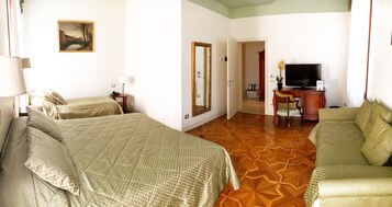 Habitación de hotel con dos camas, televisión, escritorio con silla y un cuadro en la pared.