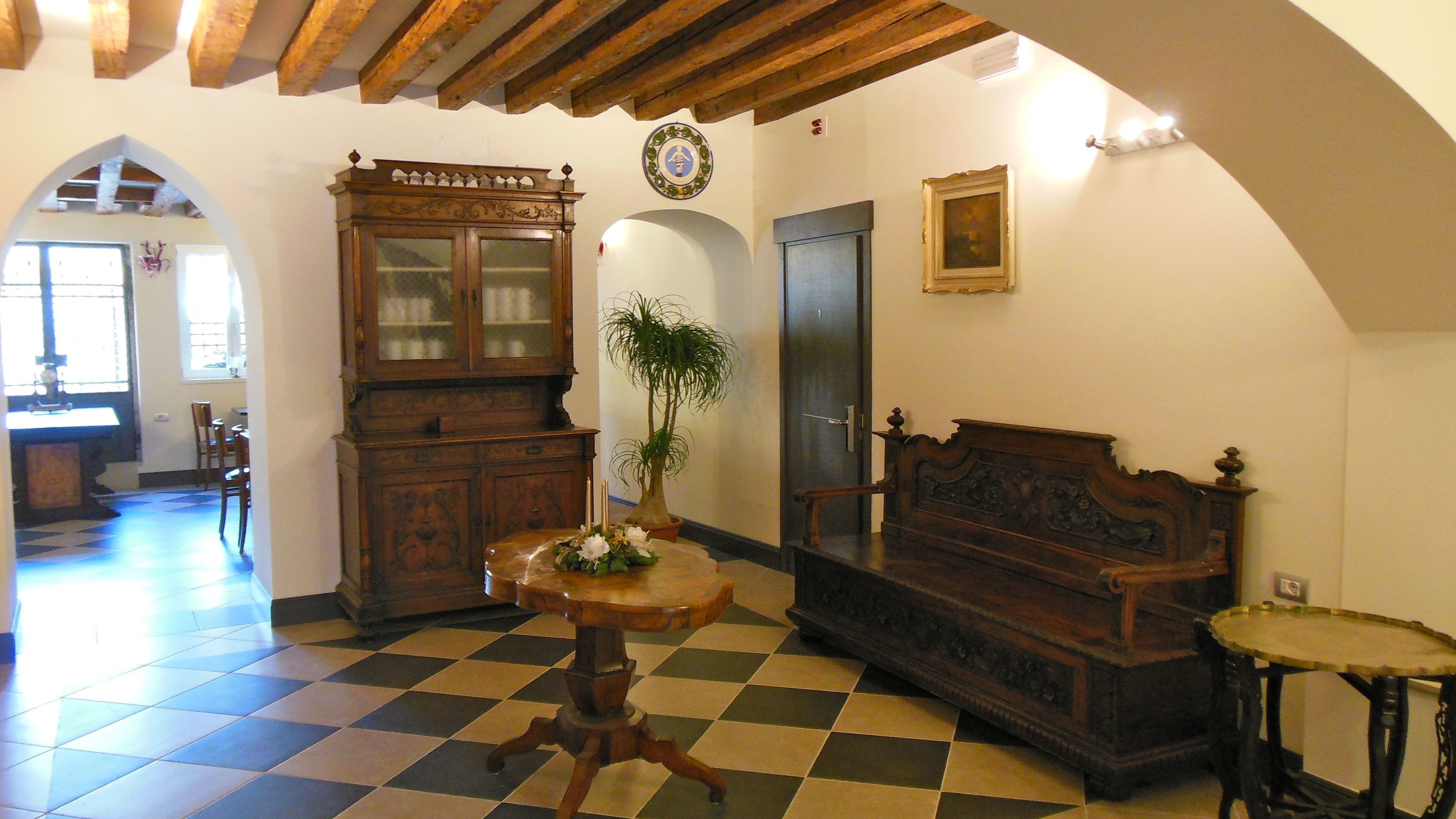 Ein Zimmer mit Schachbrettmuster-Boden, einem Holzschrank, einem Bett und einem kleinen Tisch mit Pflanze.