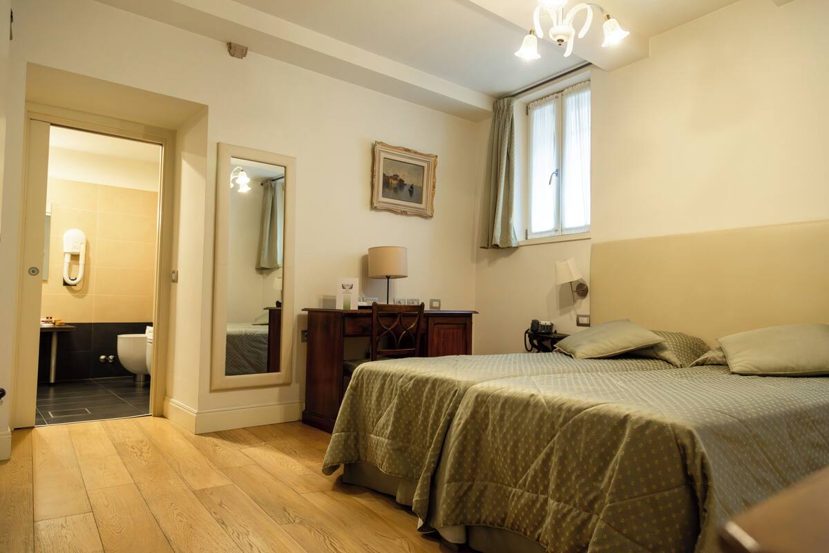 Una camera da letto con un letto, una scrivania, una sedia, uno specchio e una finestra.