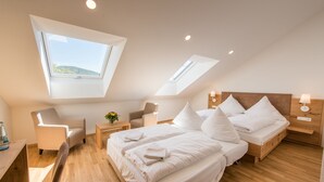 A modern bedroom with a skylight, a bed with white linens, a wooden nightstand, and a chair. - Hotel & Gasthaus Löwen (Waldkirch)