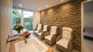 A bathroom with a stone wall, a sink, and three wicker chairs with white cushions. - Hotel & Gasthaus Löwen (Waldkirch)