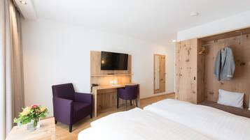 Una habitación de hotel con una cama, un escritorio con dos sillas, un televisor y un armario.