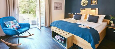 Un dormitorio moderno con cama, sillón mecedora, mesita de noche y vistas a través de un ventanal.