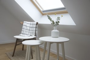 Relax in this serene space with a single chair, small table, and lush greenery.