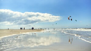 A beach with people and kites. - Lieblingsplatz Strandhotel (St. Peter-Ording)