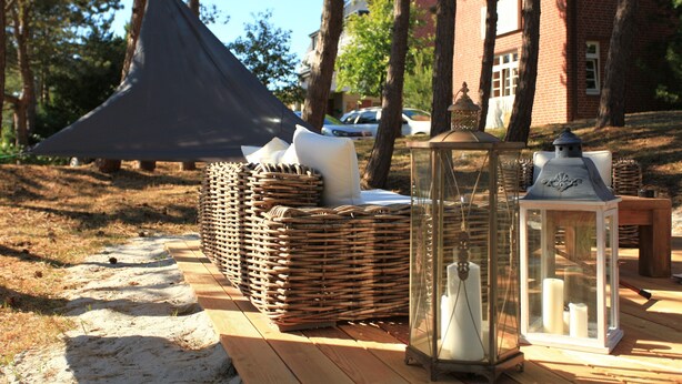 A wooden deck with wicker furniture, lanterns, and a tent. - Lieblingsplatz Strandhotel (St. Peter-Ording)