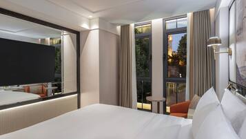 A hotel room with a large bed, a flat-screen TV, a small table, and a view of a building with a tower.