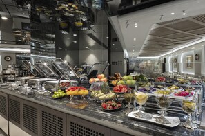 A buffet with a variety of fruits and vegetables, a glass display case, and a modern interior design.
