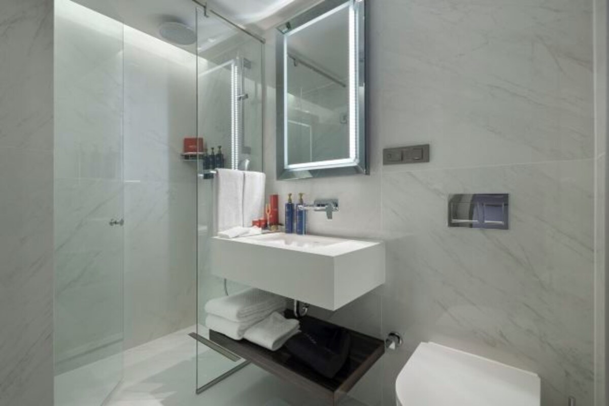 A modern bathroom with a glass shower enclosure, a white sink, and a large mirror.