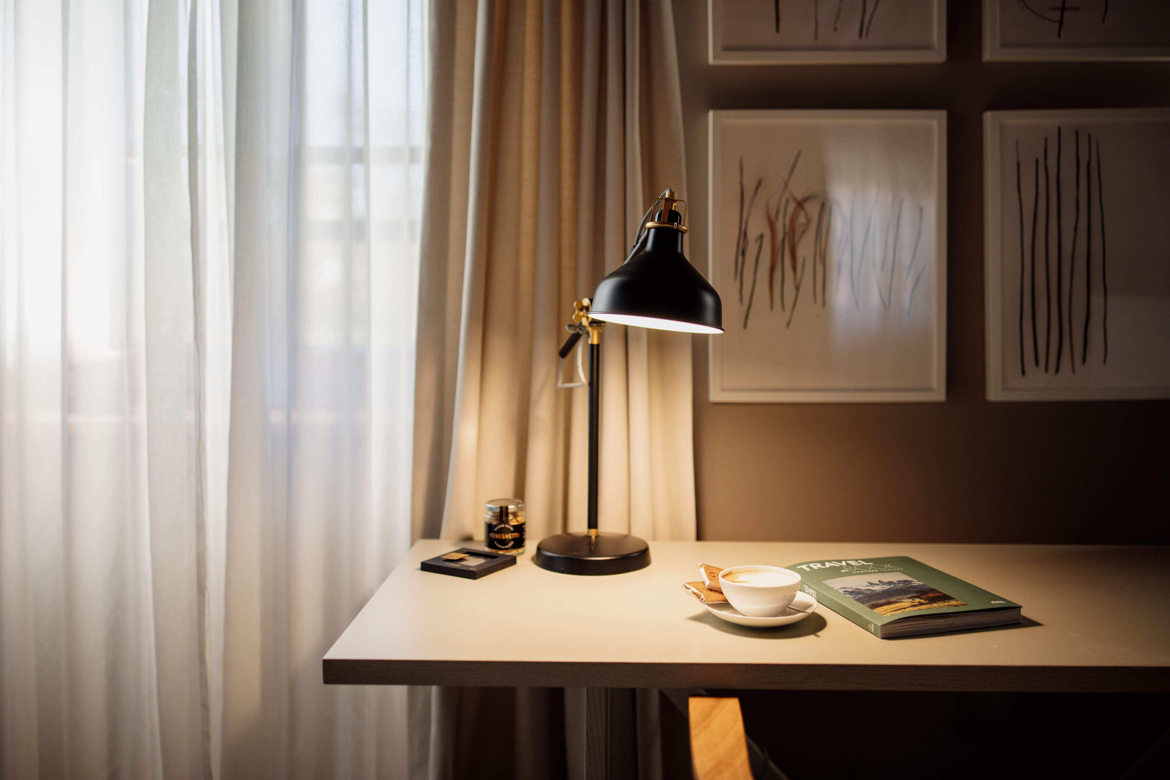 A table with a lamp, a cup, a book, and a jar of honey.