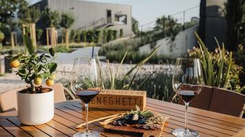 Ein Tisch mit zwei Weingläsern, einem Blumentopf, einer Holzplatte mit Speisen und einem Schild mit dem Wort 'NEIGHETTE'.