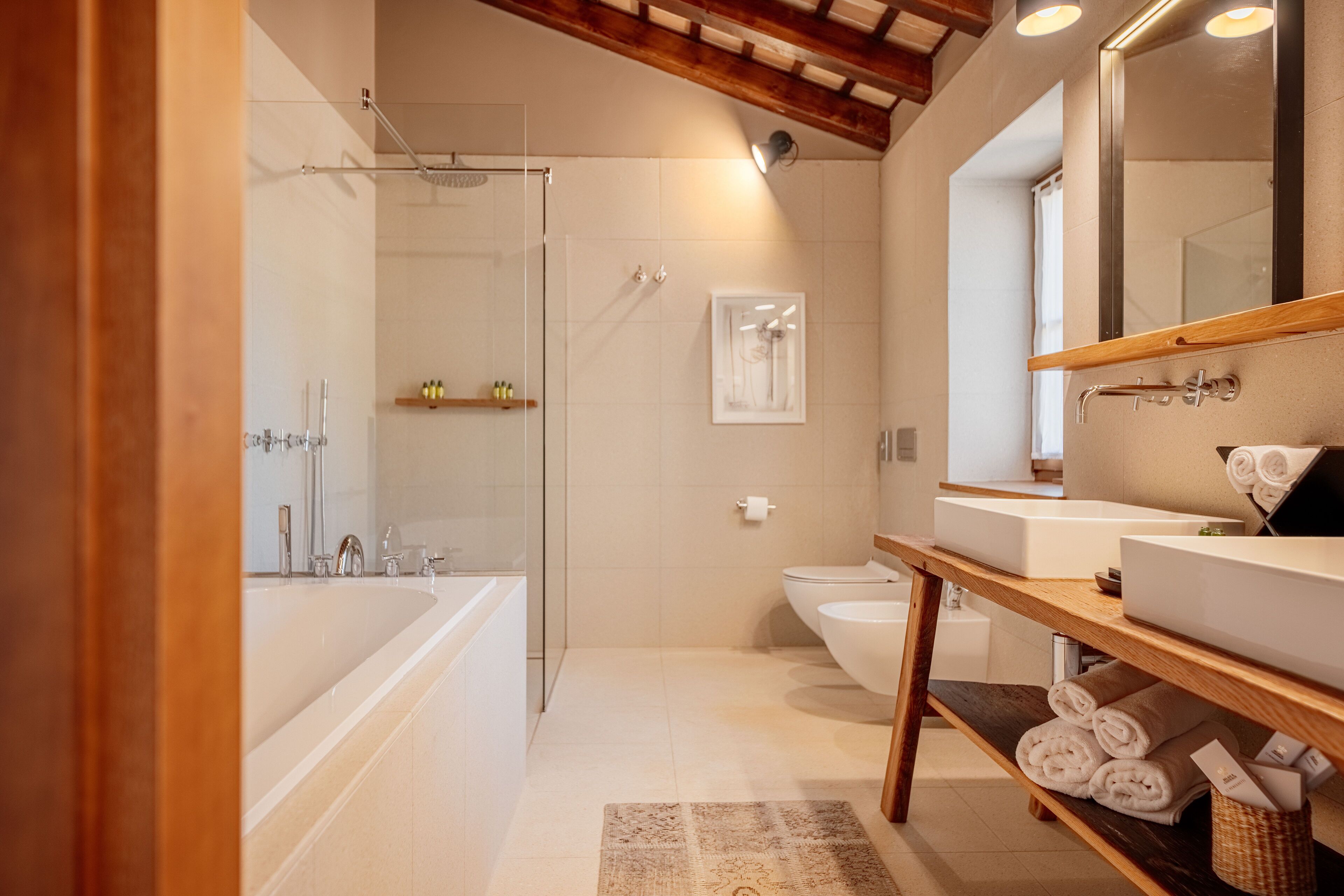 Et moderne badeværelse med badekar, bruser, toilet og et vaskeskab med spejl.