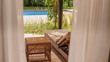 A wicker sofa with a cushion, a glass table, and a wine glass.