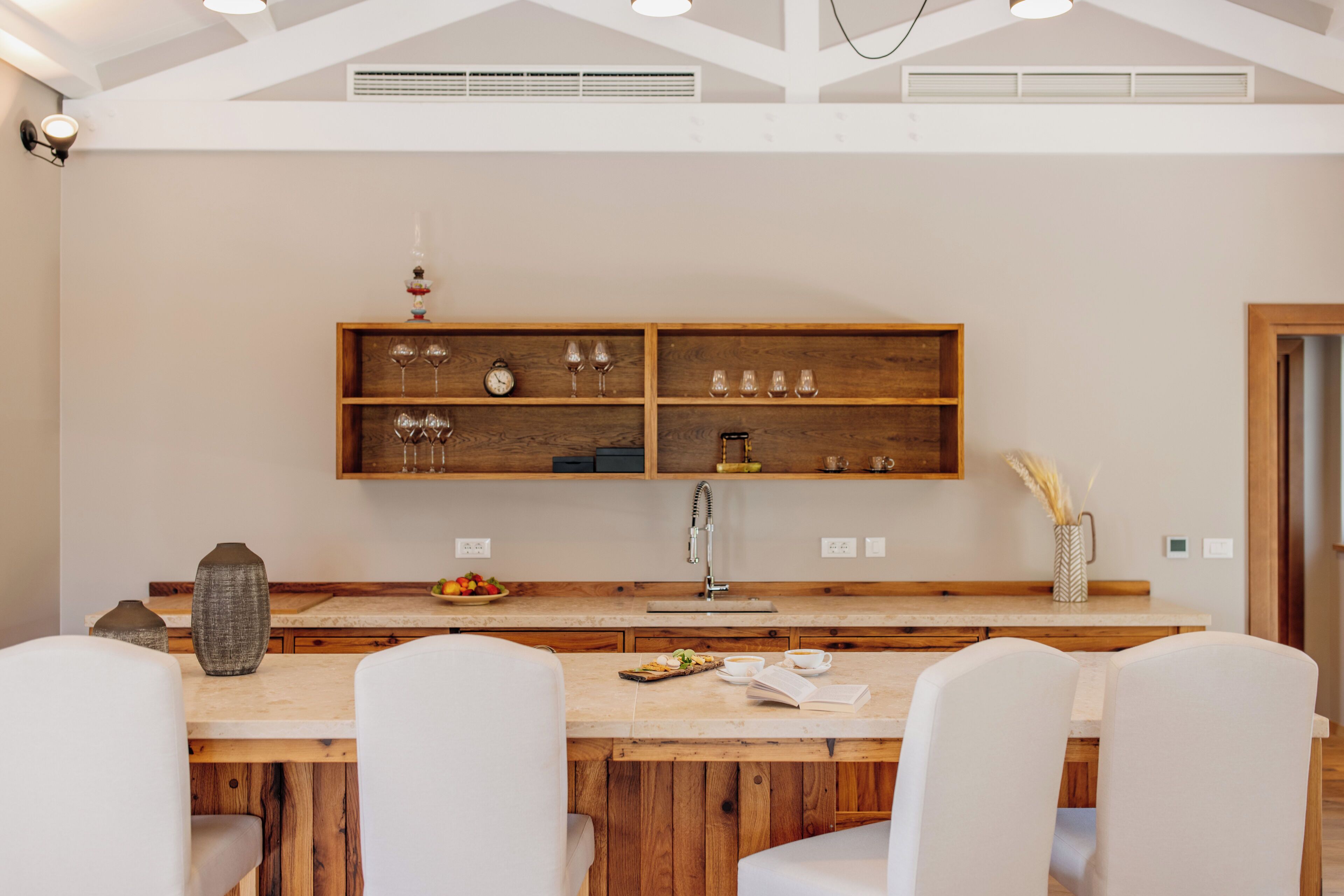 A modern kitchen with wooden shelves, a dining table, and chairs.
