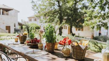 A wooden table set with various food items and plants, suggesting a dining or picnic setup in an outdoor setting.