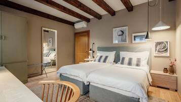 Un dormitorio con dos camas, techo de madera, mesita de noche con lámpara y una obra de arte en la pared.