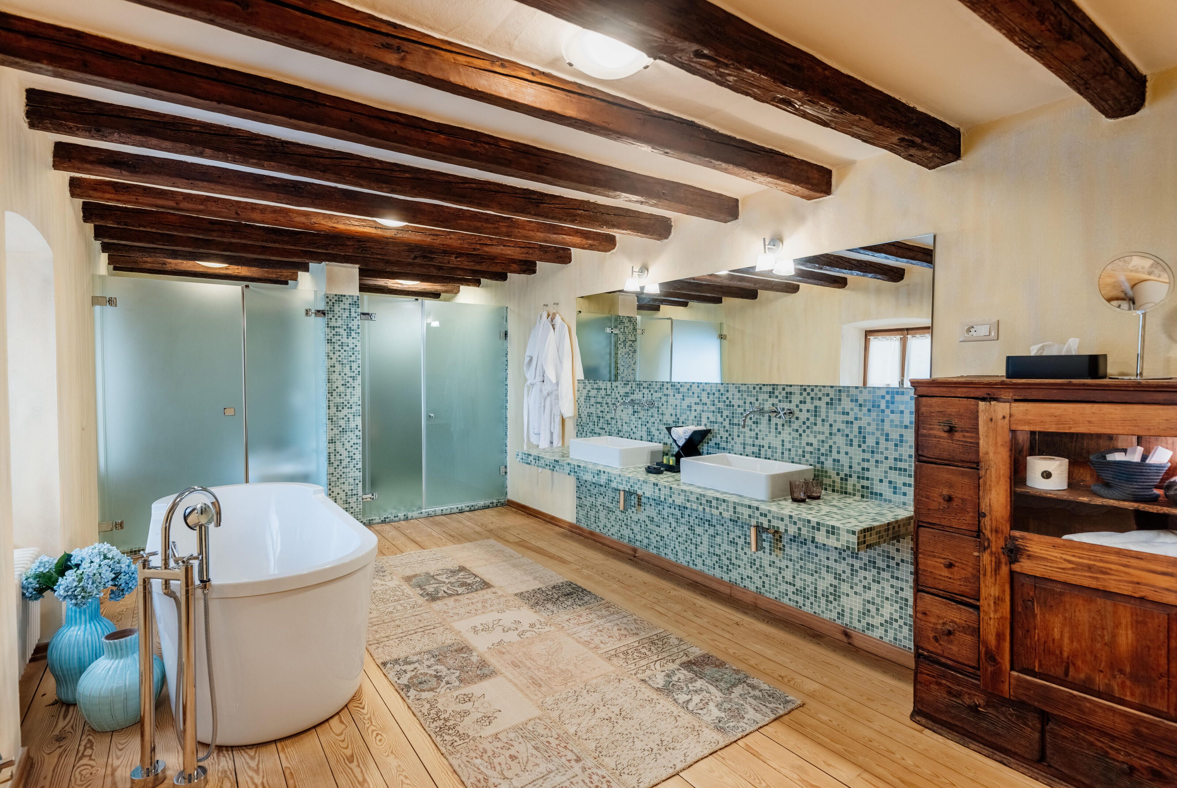 A bathroom with a freestanding bathtub, a sink, a mirror, and wooden beams on the ceiling.