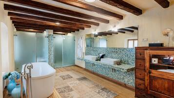 A bathroom with a freestanding bathtub, a sink, a mirror, and wooden beams on the ceiling.