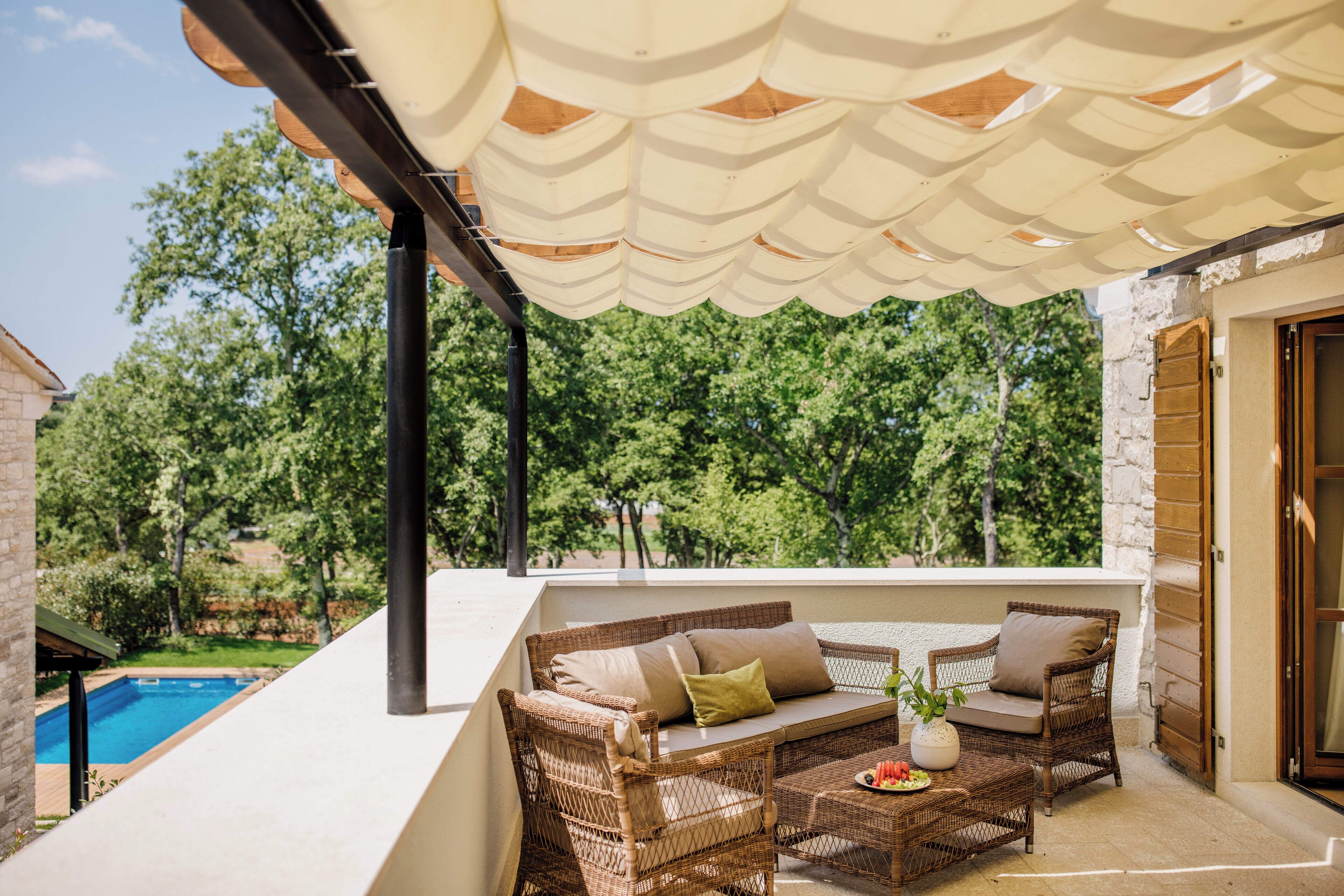 Un espacio al aire libre cubierto con mobiliario de mimbre y una piscina al fondo.