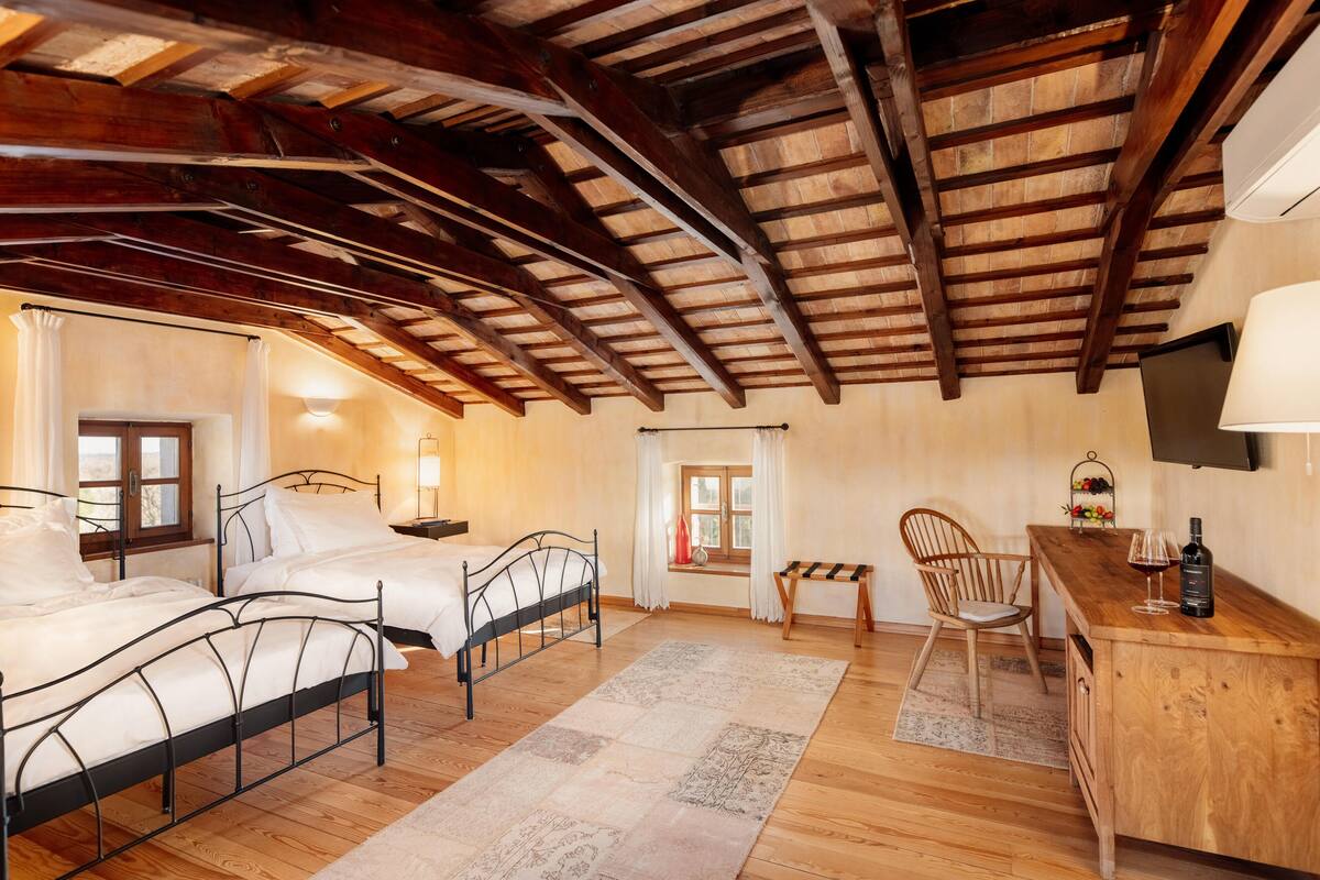 A bedroom with two beds, a wooden desk, a chair, a small table, and a TV.