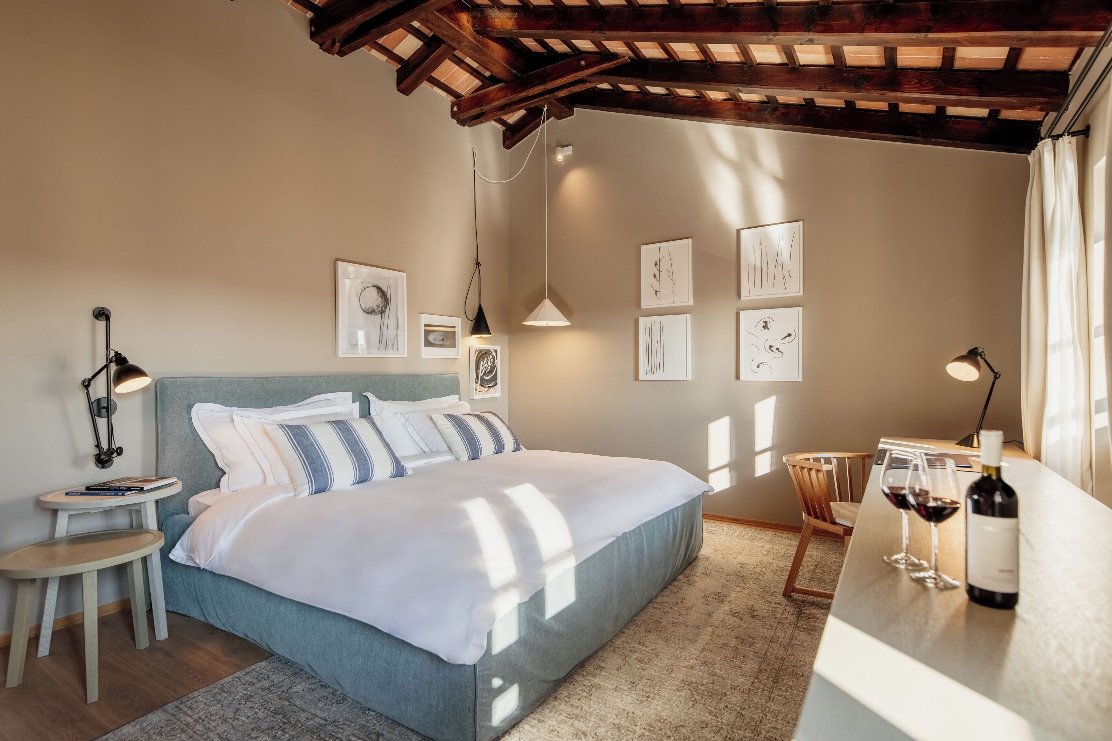 A bedroom with a bed, bedside table, lamp, and artwork on the wall.