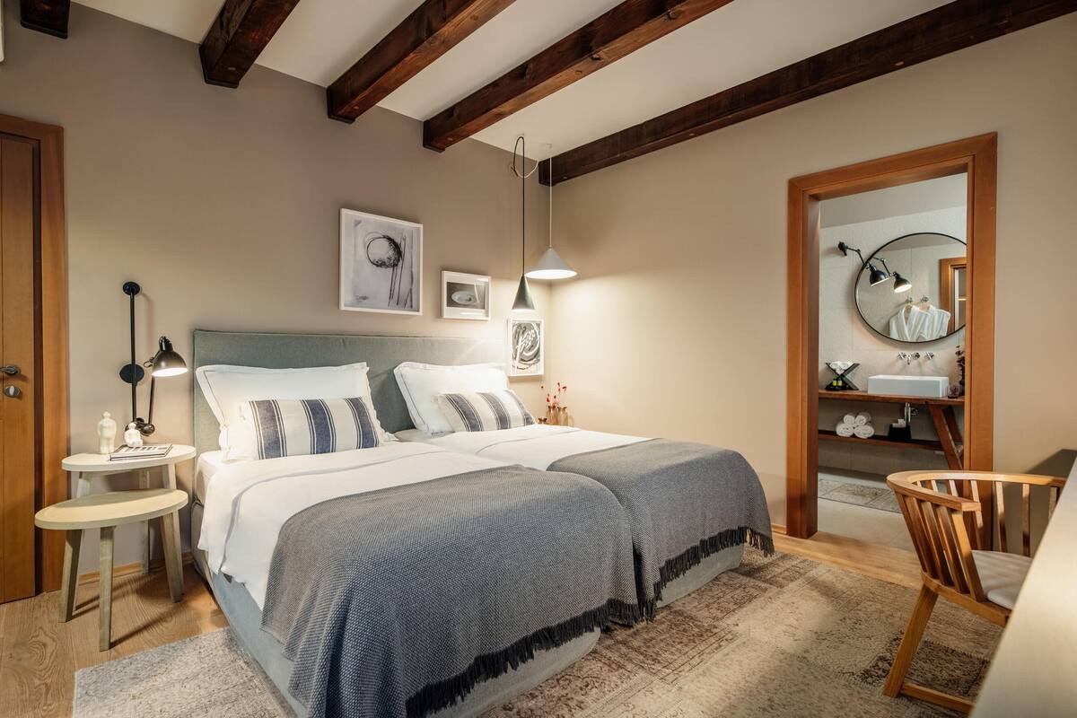 A bedroom with a large bed, bedside tables, a chair, and a mirror.