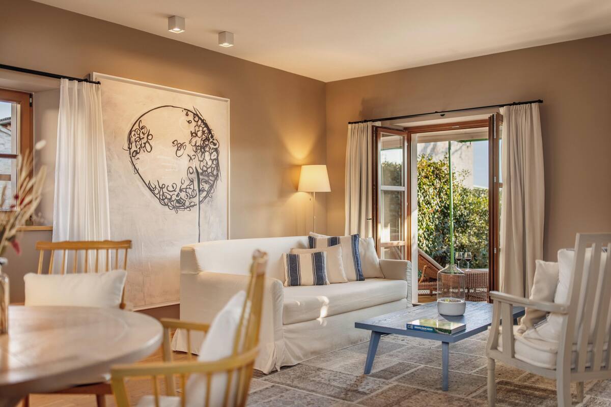 A cozy living room with a sofa, chairs, a coffee table, and a large window with curtains.