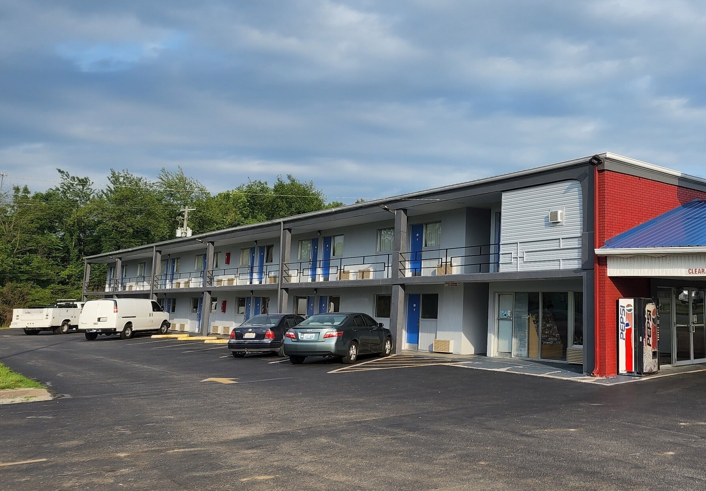 A motel with multiple rooms, a parking lot, and a visible Pepsi vending machine.
