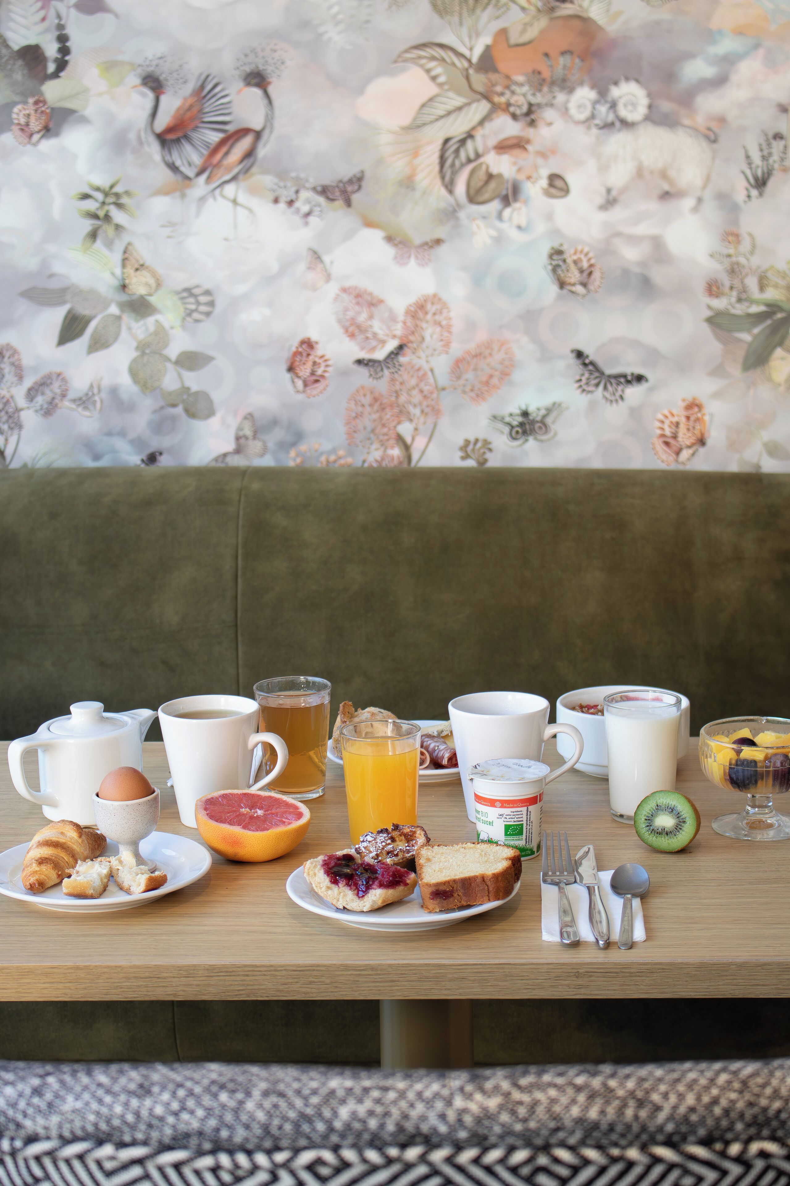 A breakfast table with various food items, drinks, and utensils.