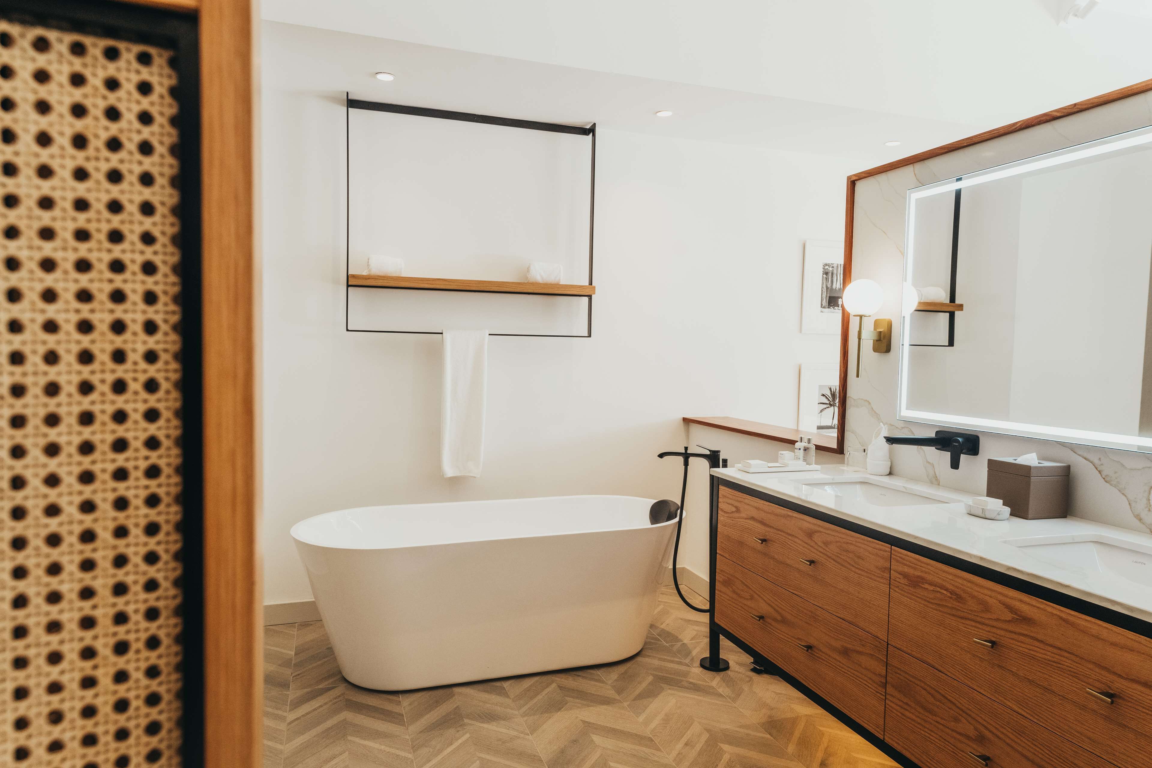 A modern bathroom with a freestanding bathtub, wooden vanity, and a large mirror.