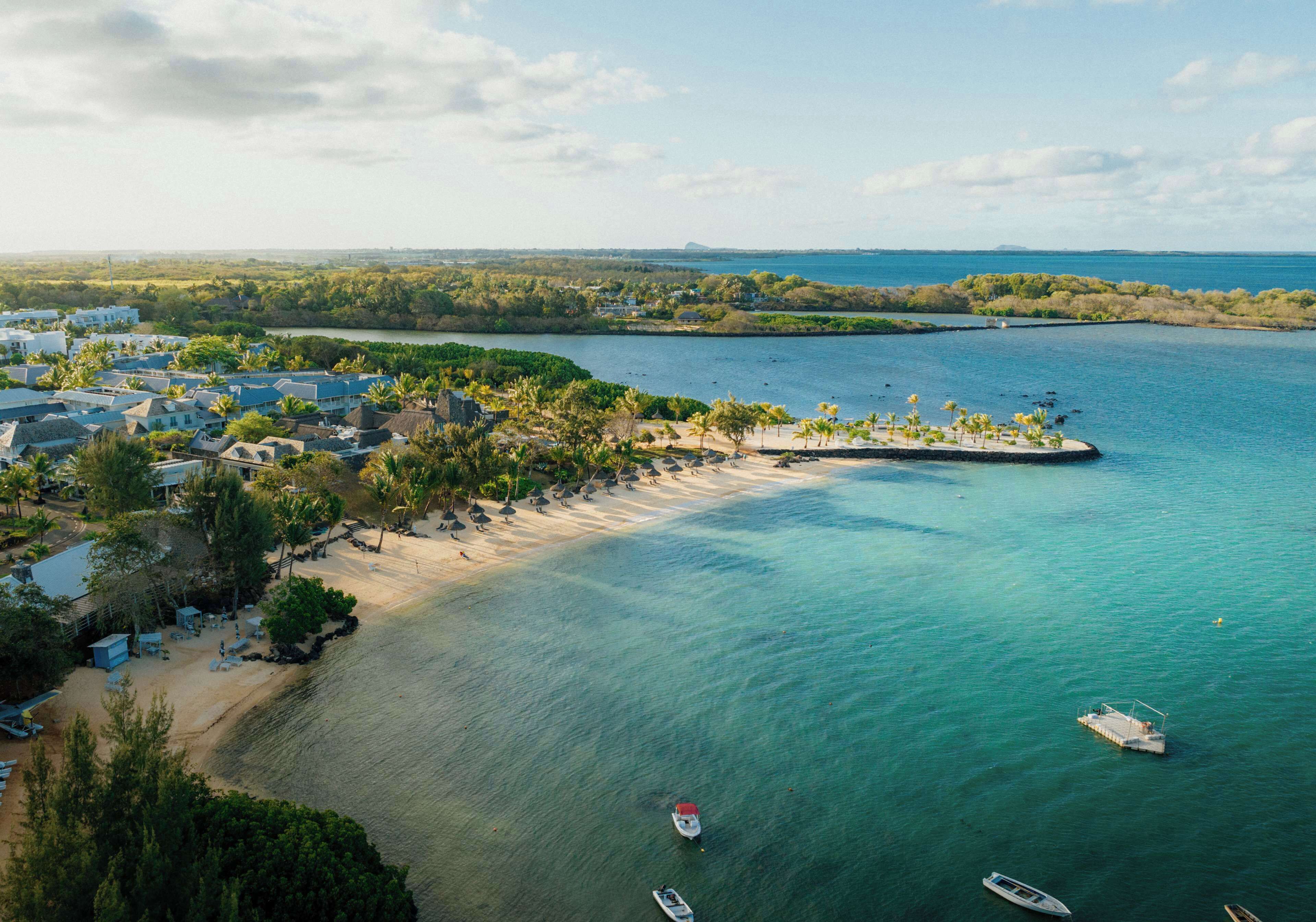 An aerial view of a coastal resort with beachfront properties, a sandy beach, and boats in the water.