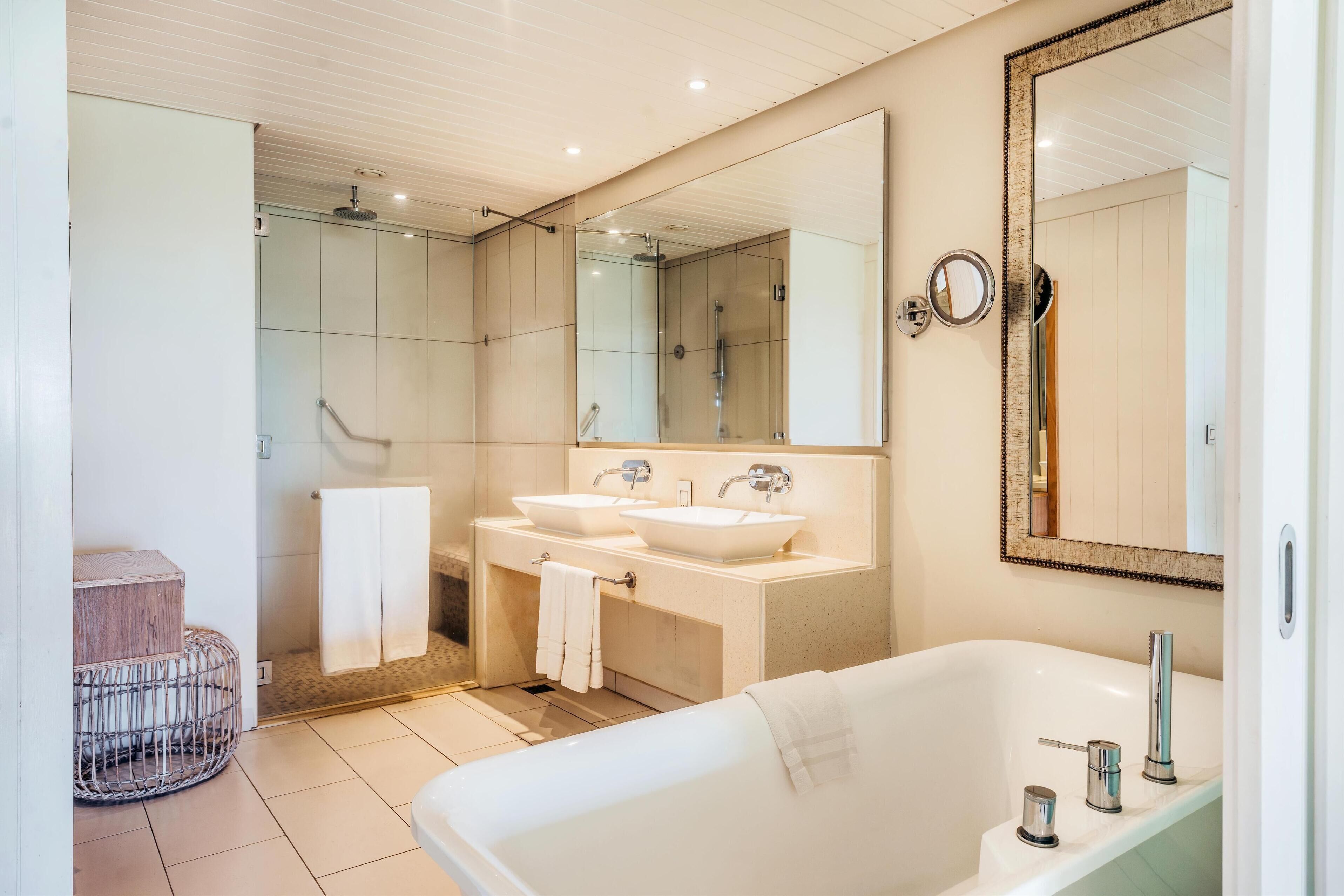 A modern bathroom with a large bathtub, two sinks, and a glass shower enclosure.