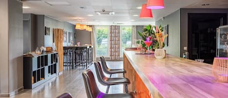 Un espacio de bar moderno con una barra alargada, varios taburetes y lámparas colgantes.