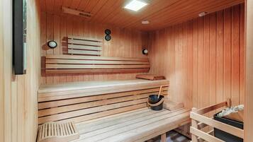 A wooden sauna with benches and a bucket of stones.