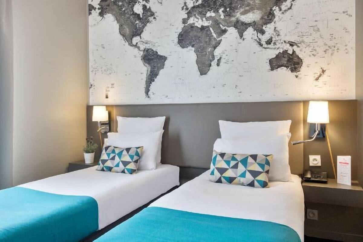 Een hotelkamer met twee bedden, een wereldkaart aan de muur en nachtlampjes.