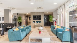 Un salon moderne avec une table de billard, des canapés de couleur turquoise, une table basse et un téléviseur.