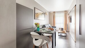 Une cuisine moderne avec un coin repas, comprenant une table avec des chaises, un luminaire suspendu et une grande fenêtre avec des rideaux.