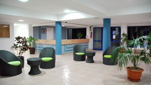 A lobby with wicker chairs, a reception desk, and potted plants. - HV Apartamentos Vista Taurito (Mogan)