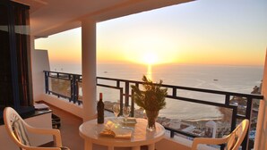 A balcony with a table, chairs, a bottle, and a glass of wine. - HV Apartamentos Vista Taurito (Mogan)