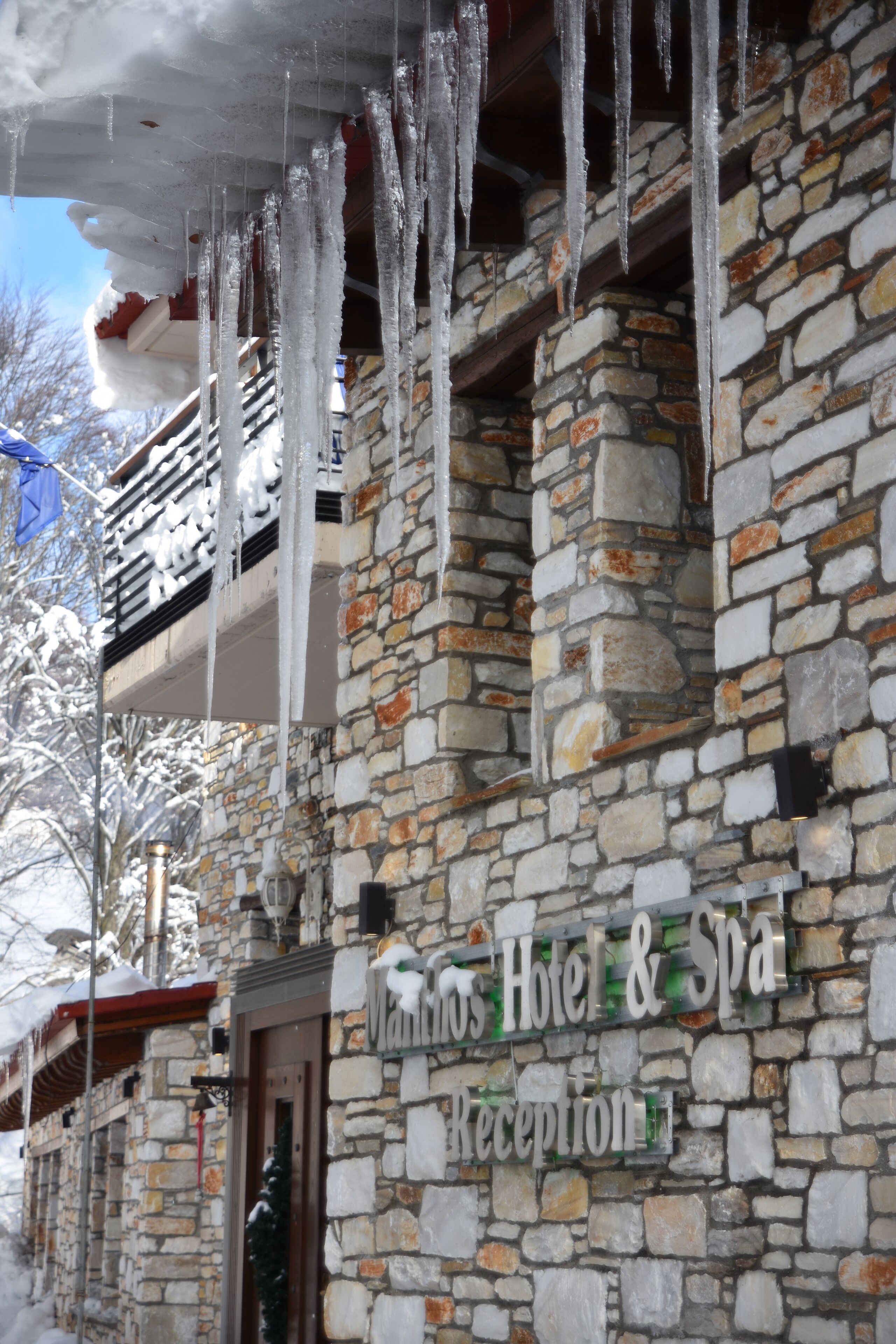 Un edificio de piedra con borbotones de hielo colgando del tejado, un cartel que dice 